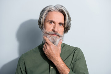 Portrait of attractive well-groomed successful grey-haired man touching beard deciding isolated...
