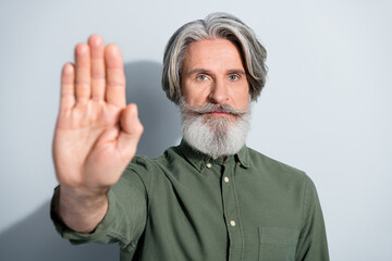Portrait of handsome serious grey-haired man showing palm stop decision isolated over gray pastel color background