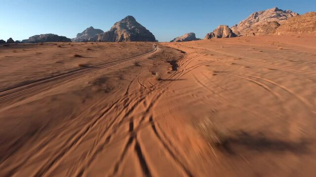 FPV chasing a 4x4 with tourists during the sunrise in the desert of Wadi Rum, Jordan
