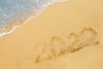2022 numbers are written on sand on sea beach. New Year 2021 is coming concept. Background for New Year's banner or advertising.