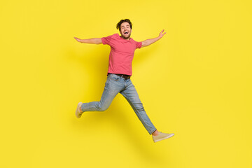 Fototapeta na wymiar Full body photo of hooray brunet young guy run wear red t-shirt jeans shoes isolated on yellow background