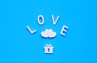 word LOVE, two hearts and a gift on a blue background