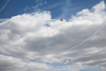 The plane is flying against the blue sky. Aerobatic figure, military aircraft.
