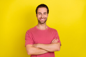 Photo of cheerful self-assured guy folded hands beaming smile wear pink t-shirt isolated yellow...