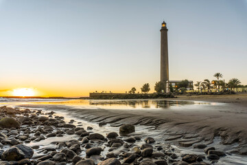 Lighthouse on rocky coast during sunset in Maspalomas, Gran Canaria, Spain
