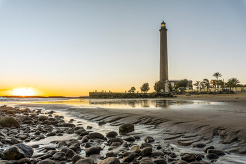 Fototapeta premium Lighthouse on rocky coast during sunset in Maspalomas, Gran Canaria, Spain