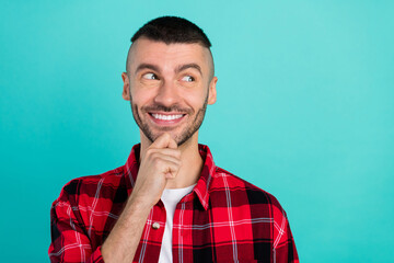 Photo of happy positive young minded man hold hand chin look empty space think idea isolated on...