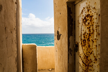 Abandoned narrow street with rusty entrance door by the ocean