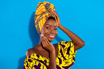 Portrait of charming positive dark skin girl hand touch cheek headwear toothy smile isolated on...