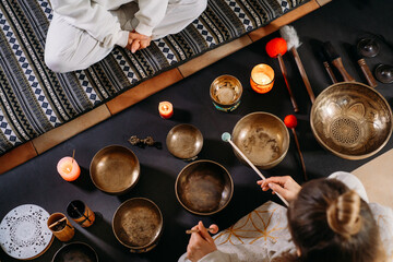 Singing bowls top view, sound healing alternative therapy. Woman playing on percussion metal music instruments. Mental health care with meditation, relaxation yoga massage