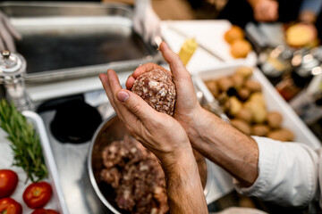 Close-up of hands of the man with piece of minced meat in form of cutlet