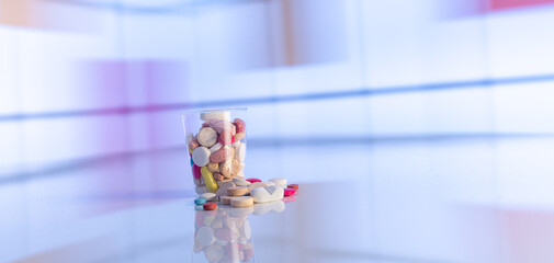 Colorful tablets with capsules and pills on mirror surface and blurred background