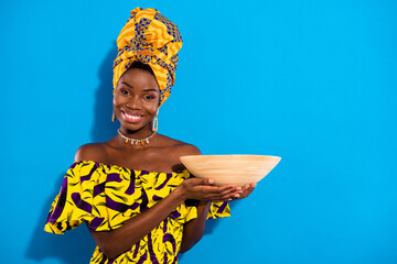 Photo of young smiling good mood positive african woman hold clay vessel plate isolated on blue...
