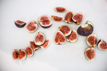 many cutted pieces of ripe purple figs on white chopping board.