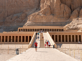 Luxor, Egypt - October 3, 2021: View of the main entrance to the temple of Queen Hatshepsut. People enter the temple on a stone staircase.. - obrazy, fototapety, plakaty