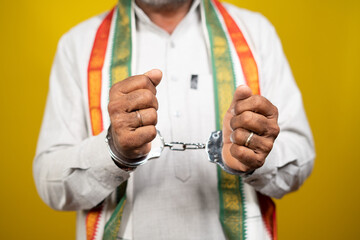 Unrecognizable Criminal Indian Politician with Hand cuffs looking on yellow background - concept of...