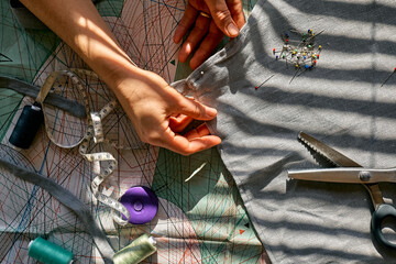 Woman is sketching pattern on a linen fabric Seamstress basting and sewing in a small studio...