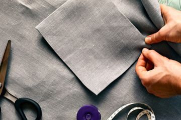 Woman is sketching pattern on a linen fabric Seamstress basting and sewing in a small studio...