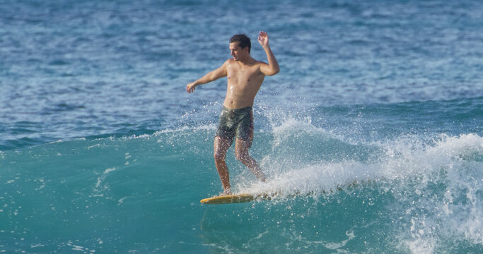 Young male surfer surfing on longboard at tropical wave