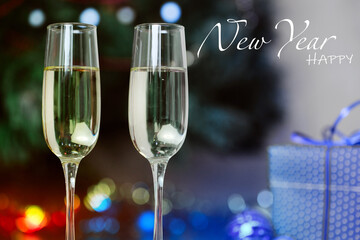 Champagne glasses and gifts, with New Year's toys near  Christmas tree decorated with colorful lights, garland and congratulatory text