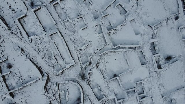 Takeoff over the old ruins of a settlement in the Caucasus mountains in winter