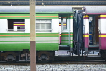 green train parking behind pole in railway station platform