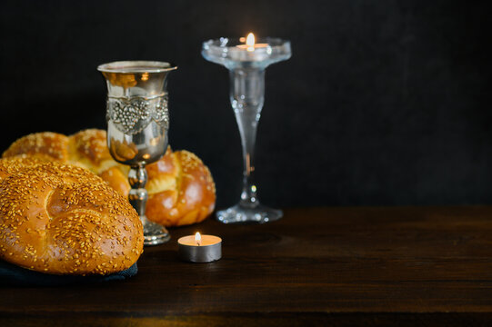 Shabbat Shalom challah bread, shabbat wine and candles on wooden table