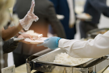 a person wearing gloves scooping food, catering, dinner time, prevent Coronavirus disease (covid 19)