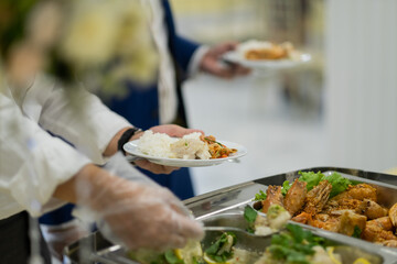 a person wearing gloves scooping food, catering, dinner time, prevent Coronavirus disease (covid 19)