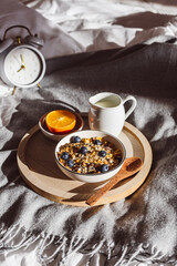Frühstück mit einer Schüssel Müsli, Obst und einer Tasse Kaffee auf einem Bett.