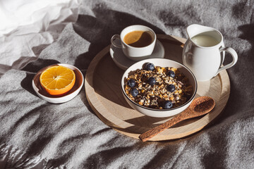 Frühstück im Bett mit einer Tasse Kaffee und Müsli in einer Schüssel. Hygge, Zuhause.