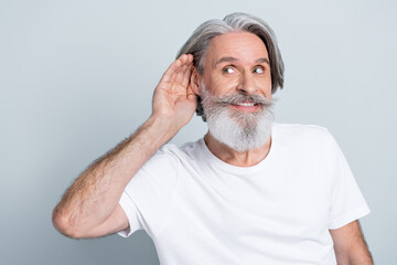 Photo of funny curious man pensioner dressed white t-shirt hearing secrets looking empty space...