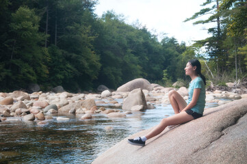 chinese woman on a larger boulder in new hampshire