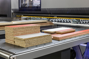 particle boards are stacked on a wood-cutting machine at a furniture