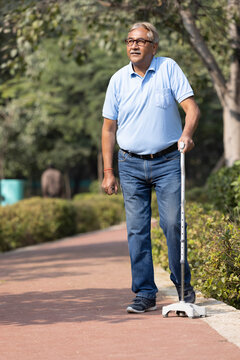 Senior man holding stick while walking at park