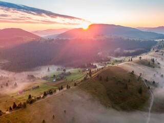 Fog in the mountain valley at dawn. Ukrainian Carpathians in the morning in the haze. Aerial drone...