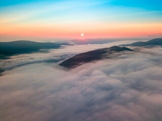 Fog in the mountain valley at dawn. Ukrainian Carpathians in the morning in the haze. Aerial drone view.