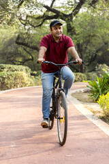 Naklejka premium Cheerful man riding bicycle at park 