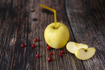 Яблоко с трубочкой на деревянном фоне.