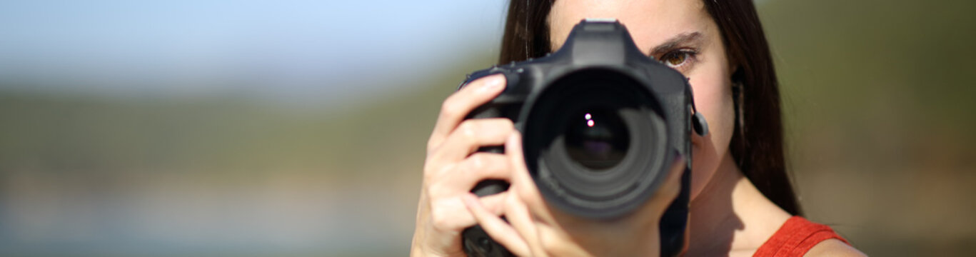 Woman photographing with dslr camera looking at you