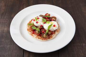 Burrata cheese on a tortilla with cherry tomatoes and basil. Delicious appetizer.Wooden background.