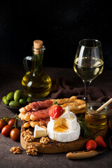 Brie cheese, camembert, grissini, jamon, wine, nuts, honey. Snacks for wine.