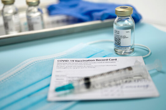 Syringe On Covid-19 Vaccination Record Card And Vials On Tray