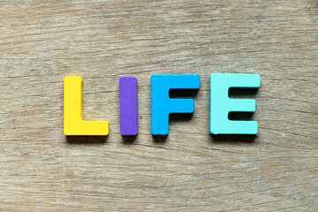 Color alphabet letter in word life on wood background