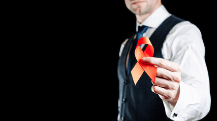 Hiv ribbon. Red ribbon in hiv world day in man hand. Awareness aids and cancer symbol on black...