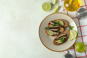 Concept of tasty snack with sandwiches with sprats on light textured background