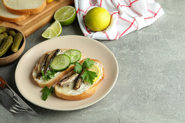 Concept of tasty snack with sandwiches with sprats on gray textured background