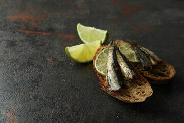 Delicious sandwiches with sprats on textured background