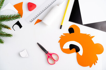 the process of making a children's New Year tiger mask with a child made of colored paper, top view, symbol 2022, step-by-step