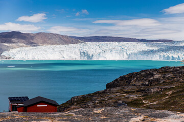 Blue and white mass of ice, glacier with blue ocean and the rocks in the front, Greenland, Europe 
